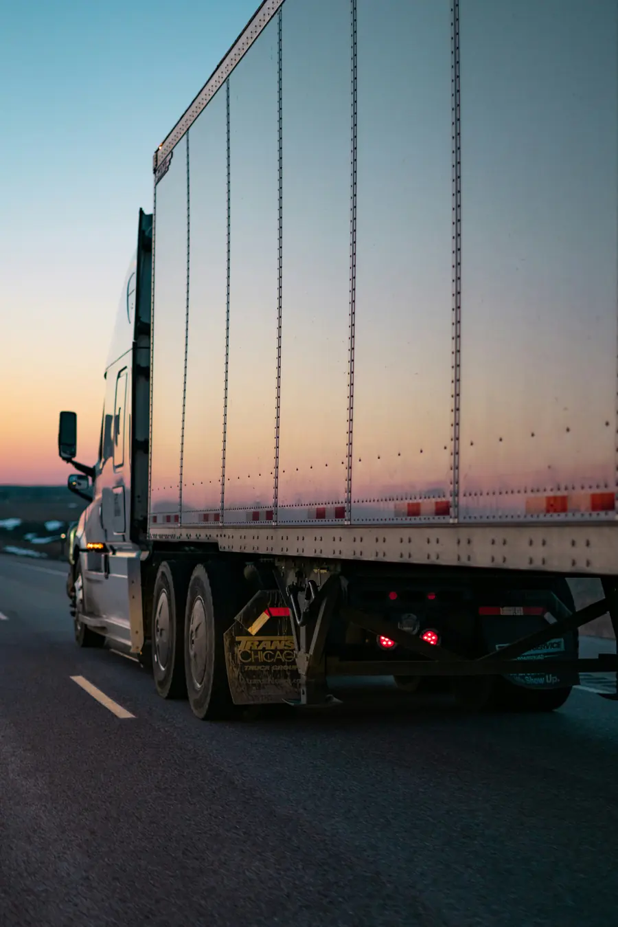 Tractor and 53-foot dry van trailer on the highway at sunset